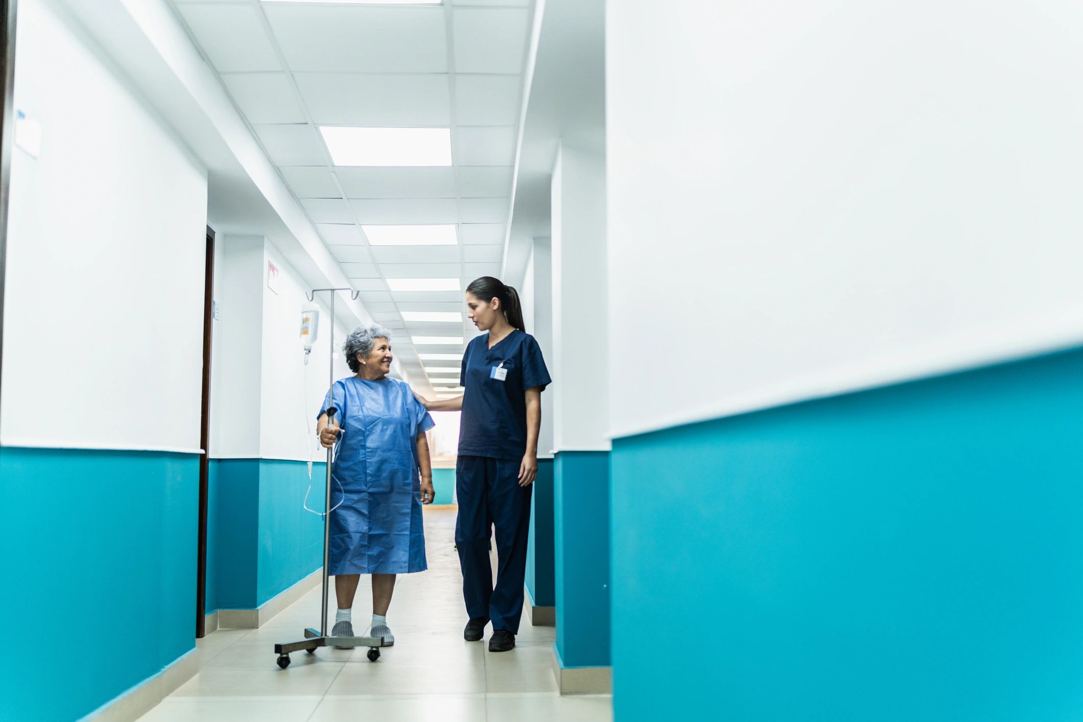 Nurse assisting patient in hospital corridor